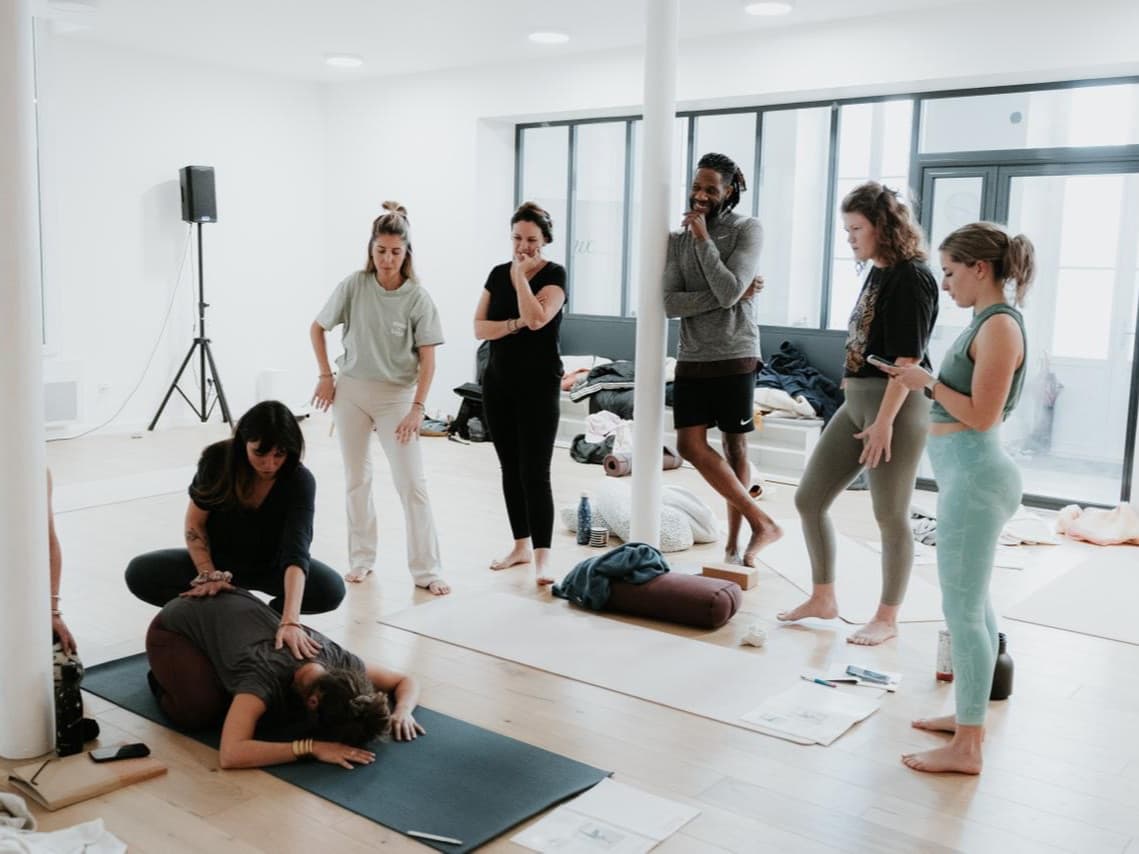 Ajustement guidé pendant une formation de yoga prénatal, le groupe de stagiaires observe