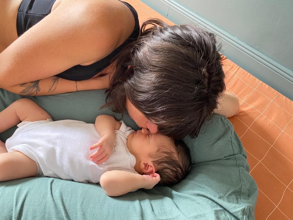 Jeune mère penchée sur son nouveau-né endormi, dans l’intimité de la maison